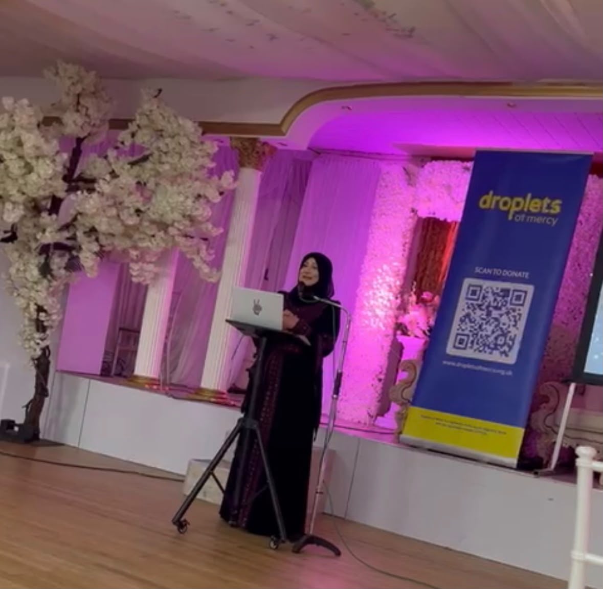 Speaker addressing guests at a Droplets of Mercy charity event
