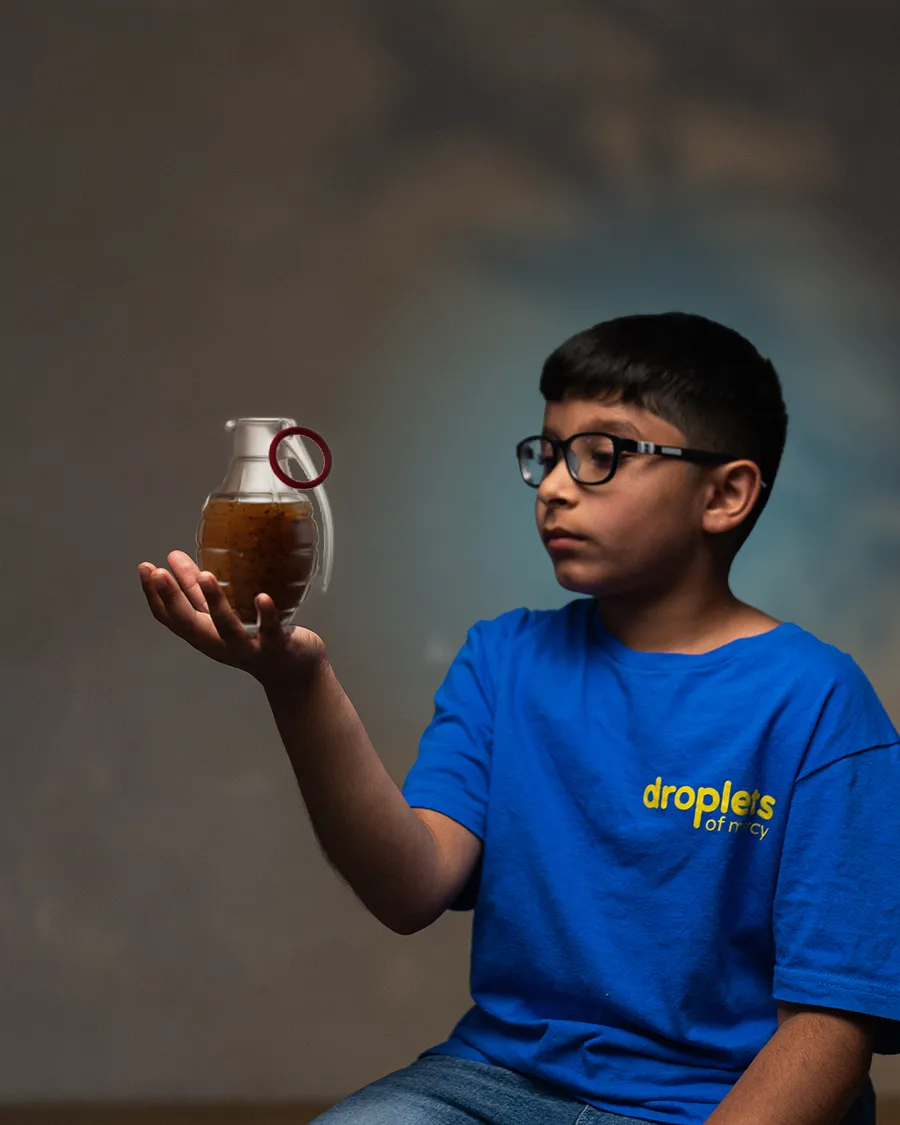 A child holding dirty water shaped like a grenade